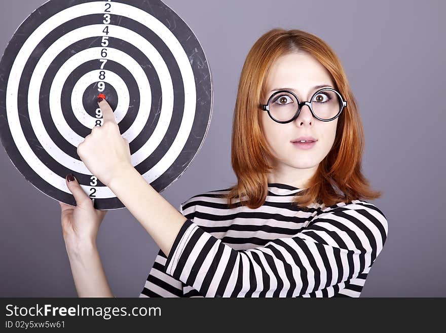 Red-haired girl with dartboard. Studio shot.