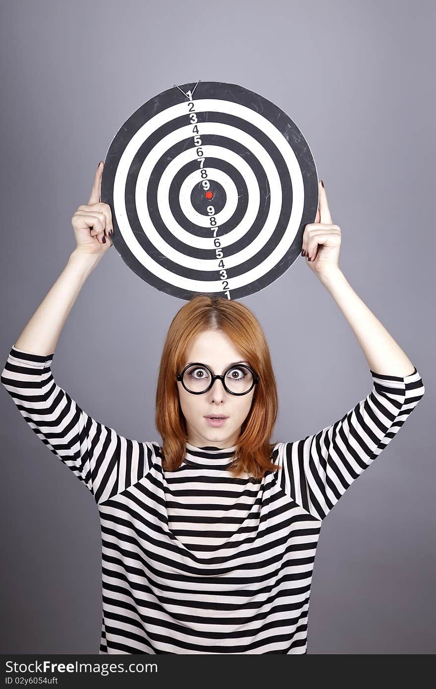 Red-haired girl with dartboard. Studio shot.