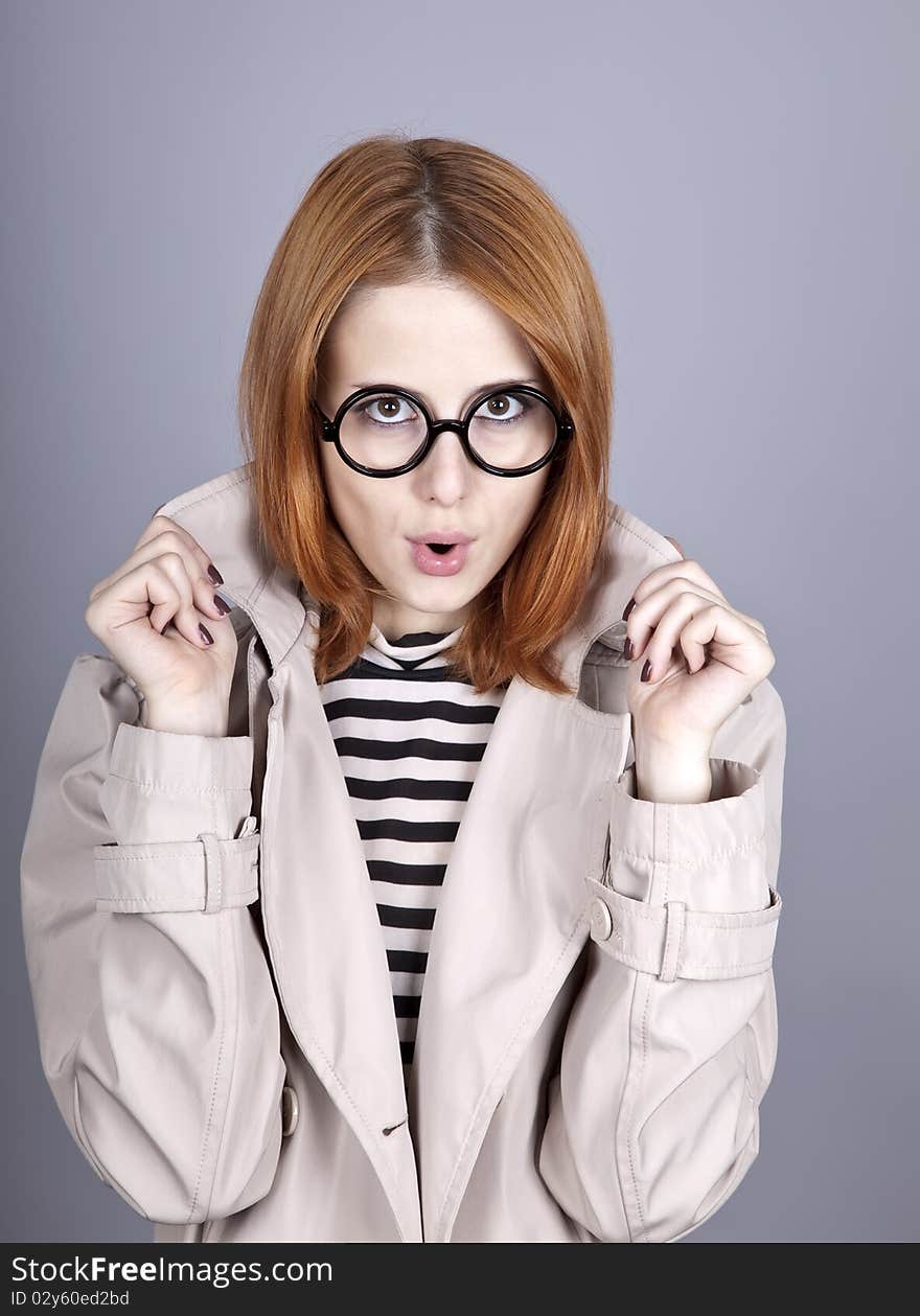 Young red-haired girl in glasses and cloak. Studio shot.