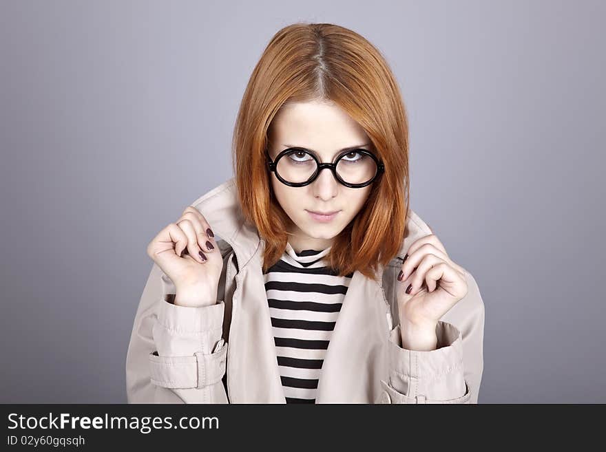 Young red-haired girl in glasses and cloak. Studio shot.