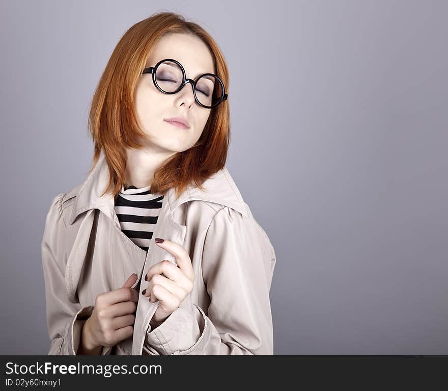 Young red-haired girl in glasses and cloak. Studio shot.