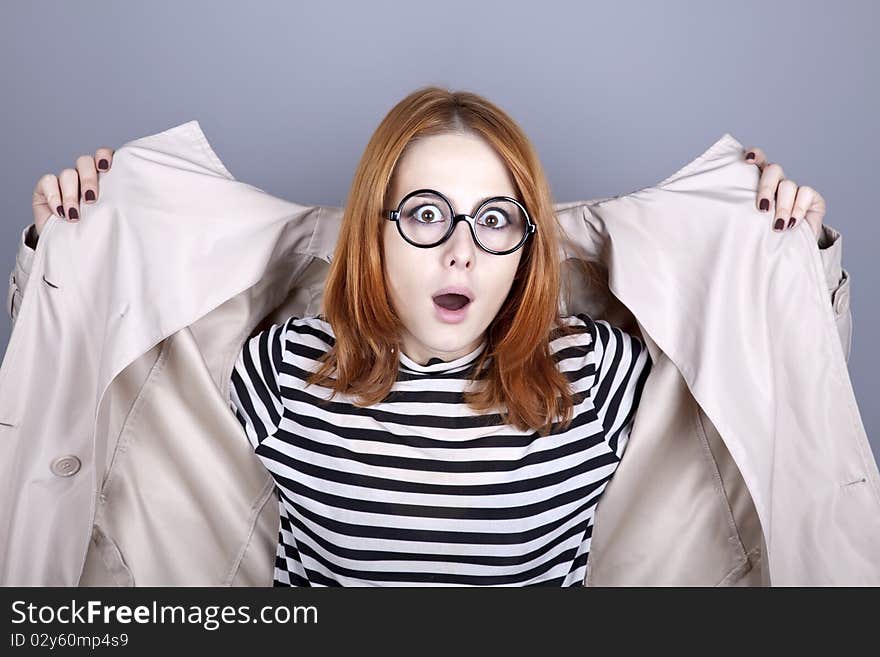 Young red-haired girl in glasses and cloak. Studio shot.