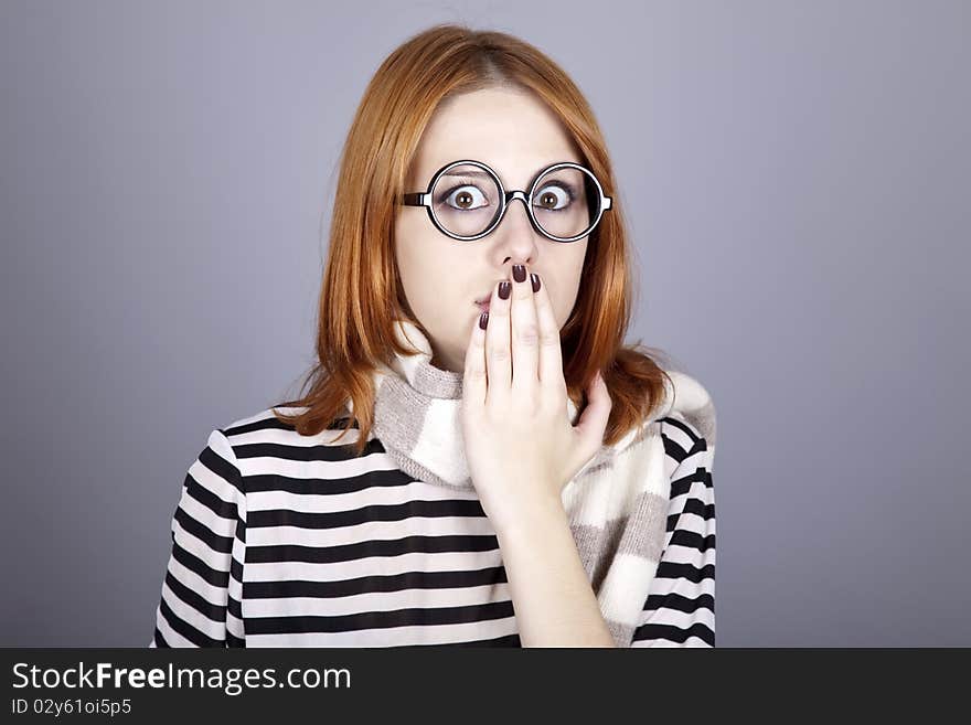 Surprised red-haired girl in glasses and scarf. Studio shot.