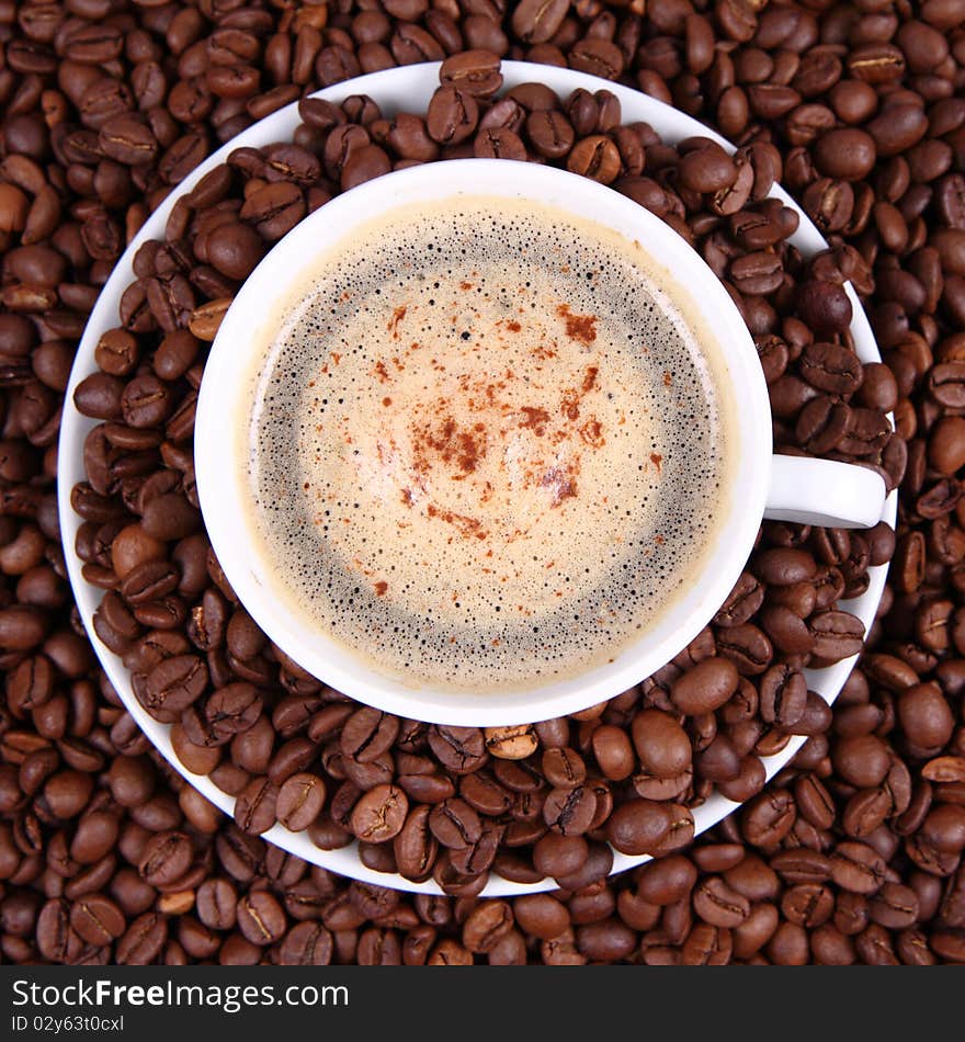 Cup of coffee with sprinkled with cinnamon with coffee beans around it