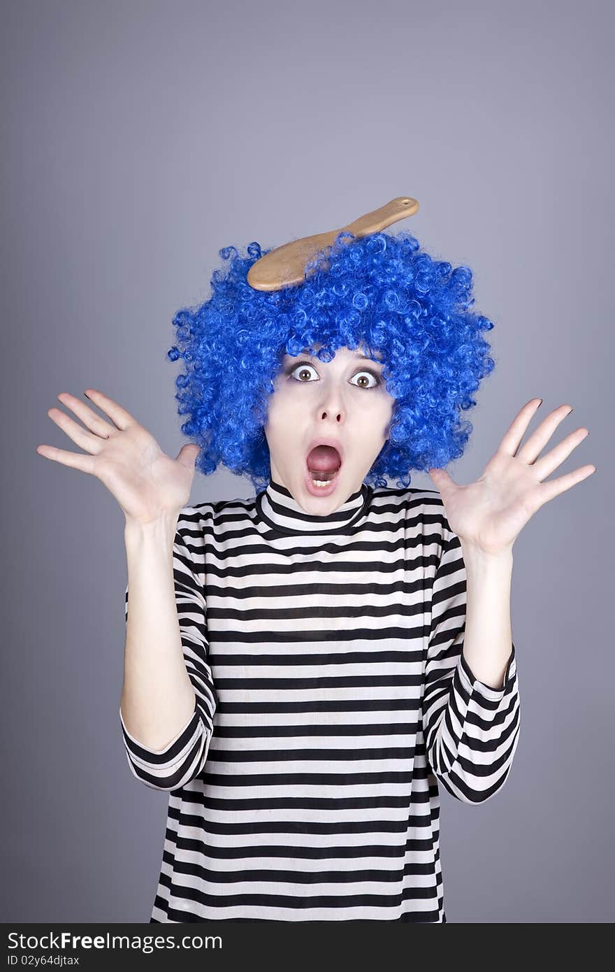 Surprised blue hair girl with stuck comb. Studio shot.