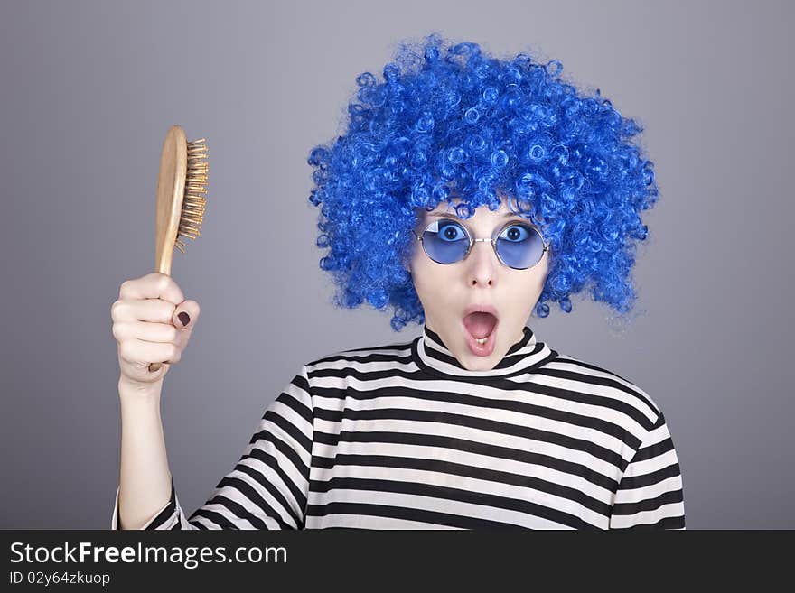 Surprised blue hair girl with comb. Studio shot.