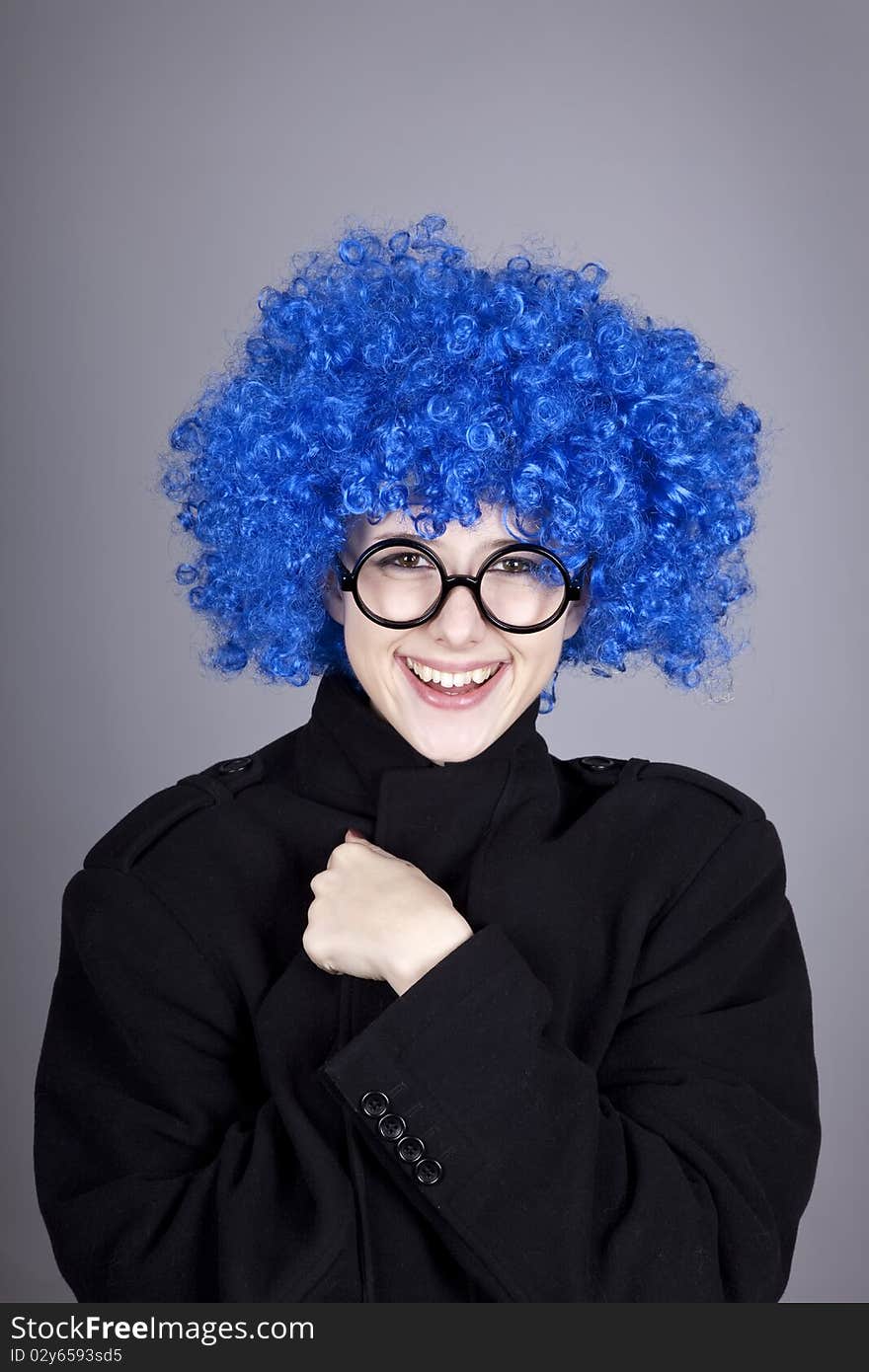 Funny blue-hair girl in glasses and black coat. Studio shot.