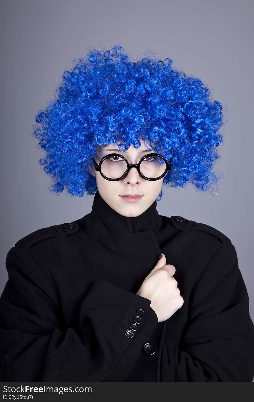 Funny blue-hair girl in glasses and black coat. Studio shot.