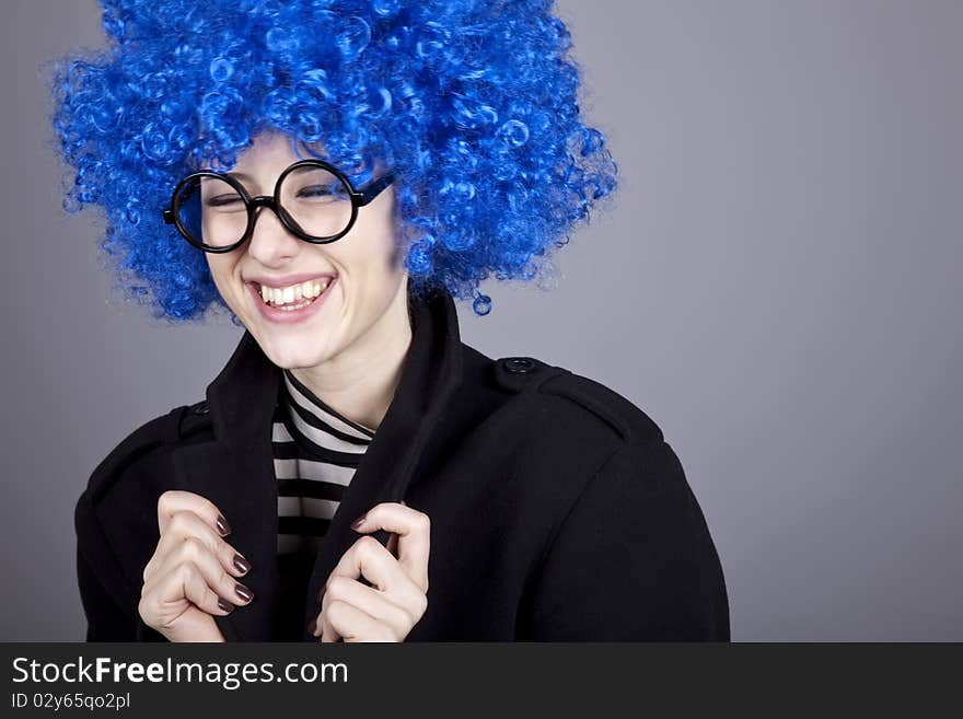 Funny blue-hair girl in glasses and black coat. Studio shot.