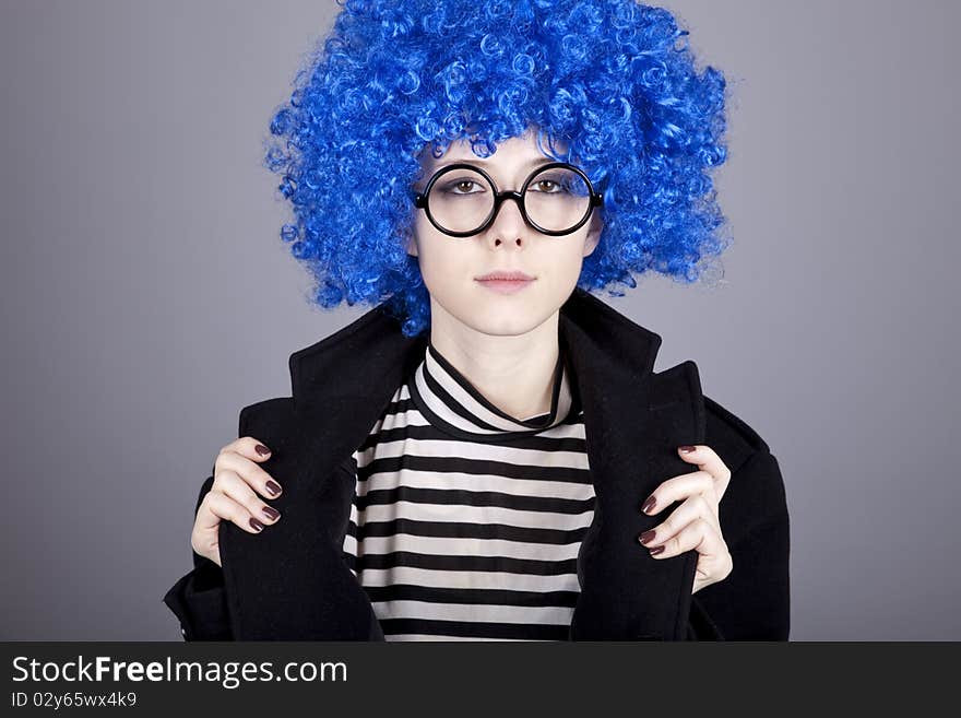 Funny blue-hair girl in glasses and black coat. Studio shot.