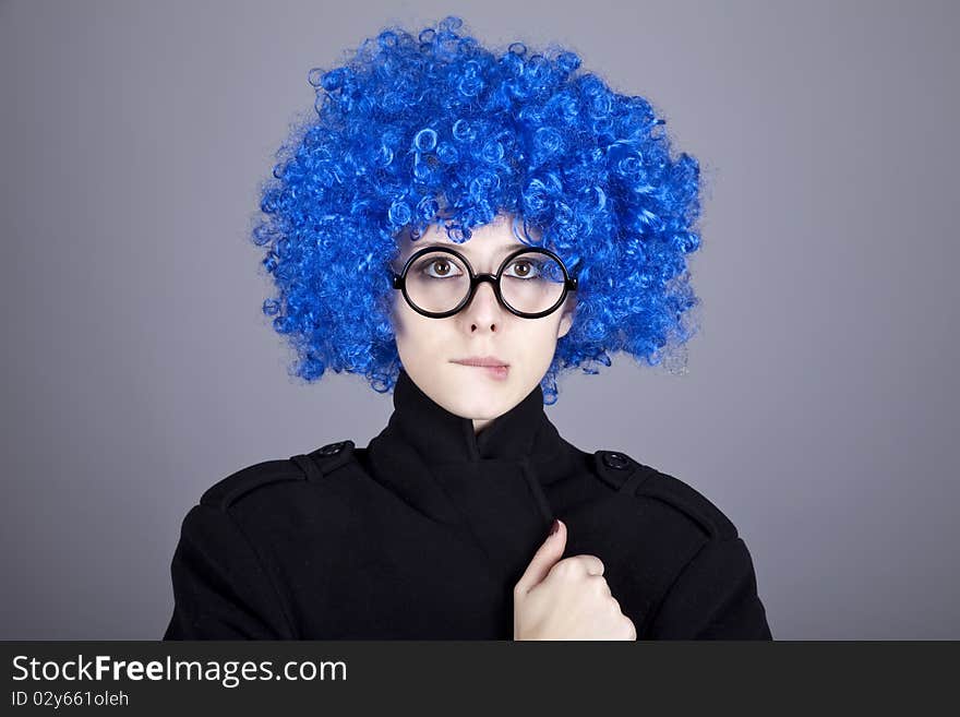 Funny blue-hair girl in glasses and black coat. Studio shot.