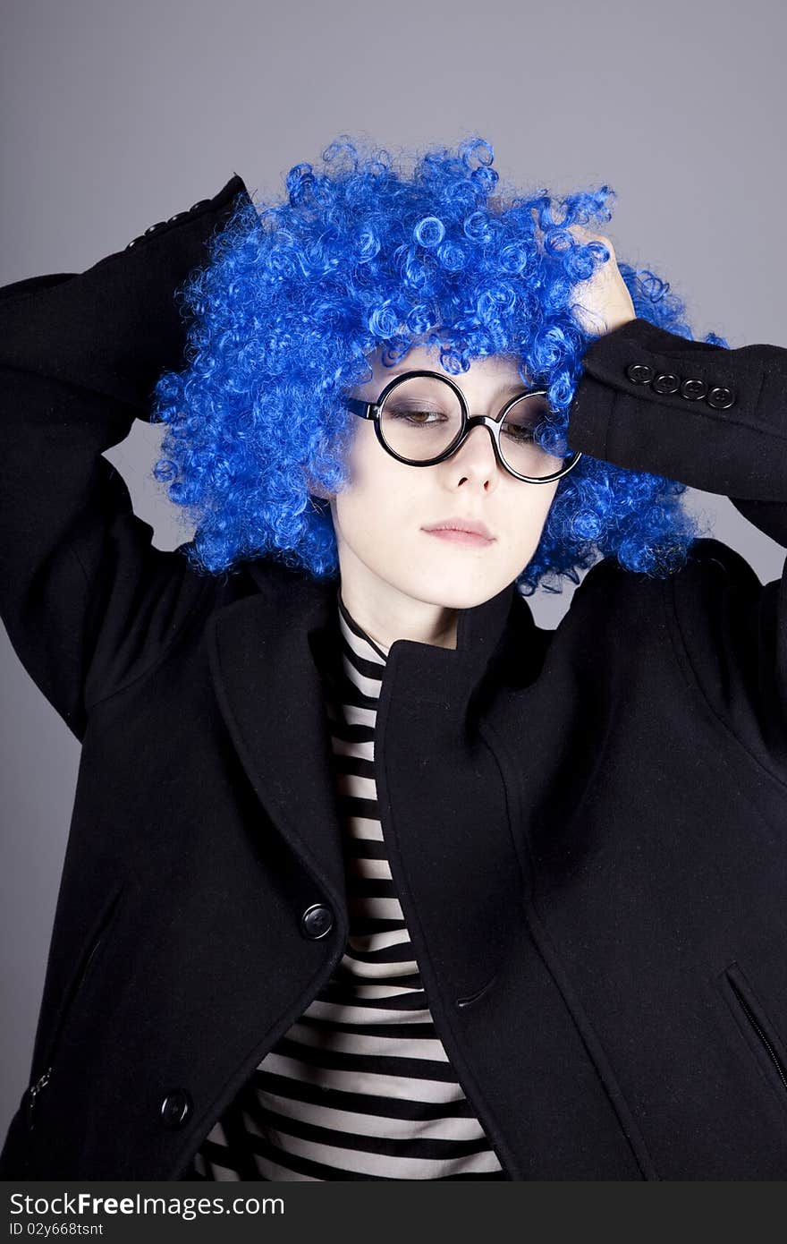 Funny blue-hair girl in glasses and black coat. Studio shot.