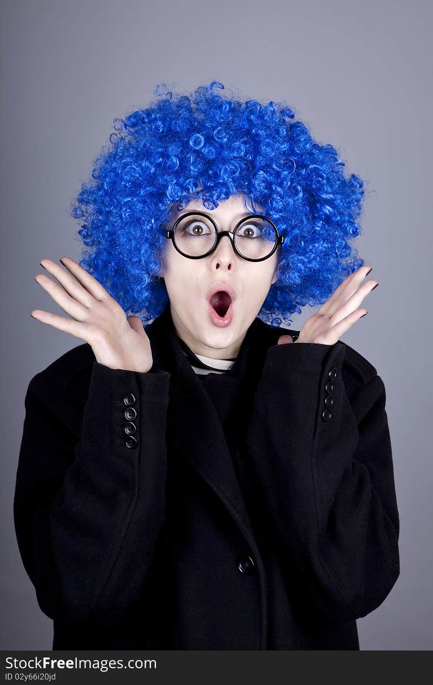 Funny blue-hair girl in glasses and black coat. Studio shot.