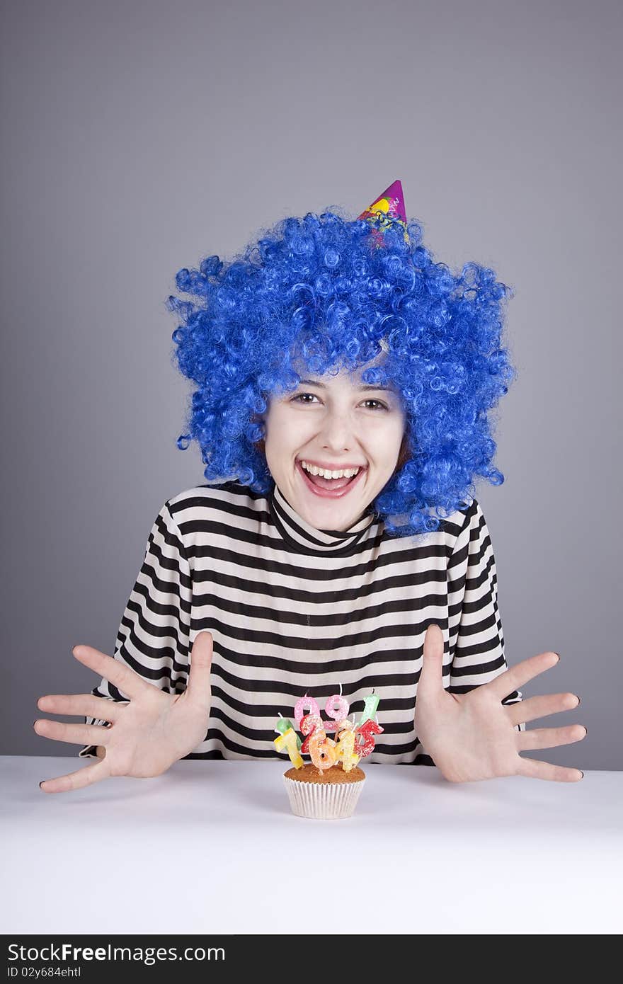 Funny blue-hair girl with cake. Studio shot.