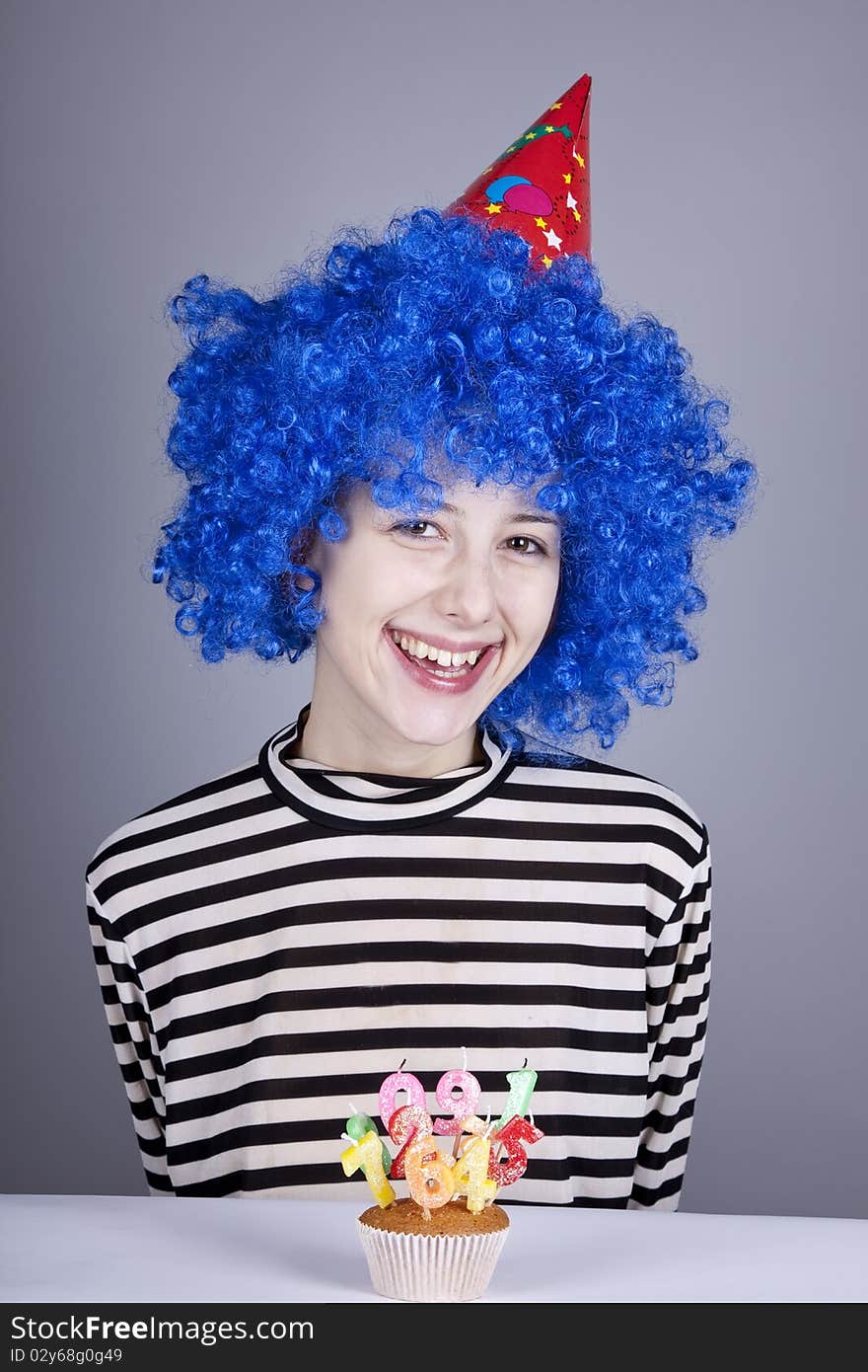 Funny blue-hair girl with cake. Studio shot.