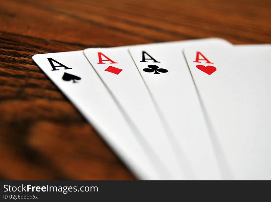 A group of four playing card aces on a stained oak wooden table. A group of four playing card aces on a stained oak wooden table.