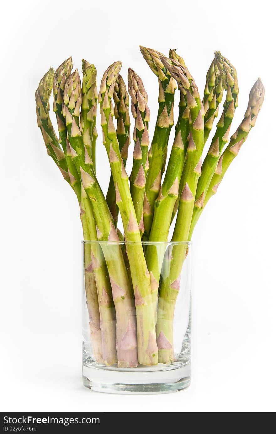 Bunch of fresh green asparagus standing in a glass on a white background