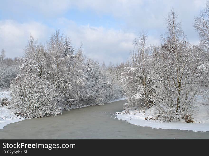 Snow-covered landscape with the river at the winter. Forest in the Snow. Trees in the Snow.