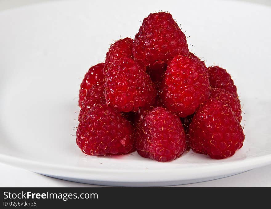 A pyramide of fresh raspberries on a white plate. A pyramide of fresh raspberries on a white plate