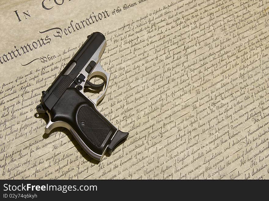 An automatic handgun rests on the Declaration of Independence. An automatic handgun rests on the Declaration of Independence.