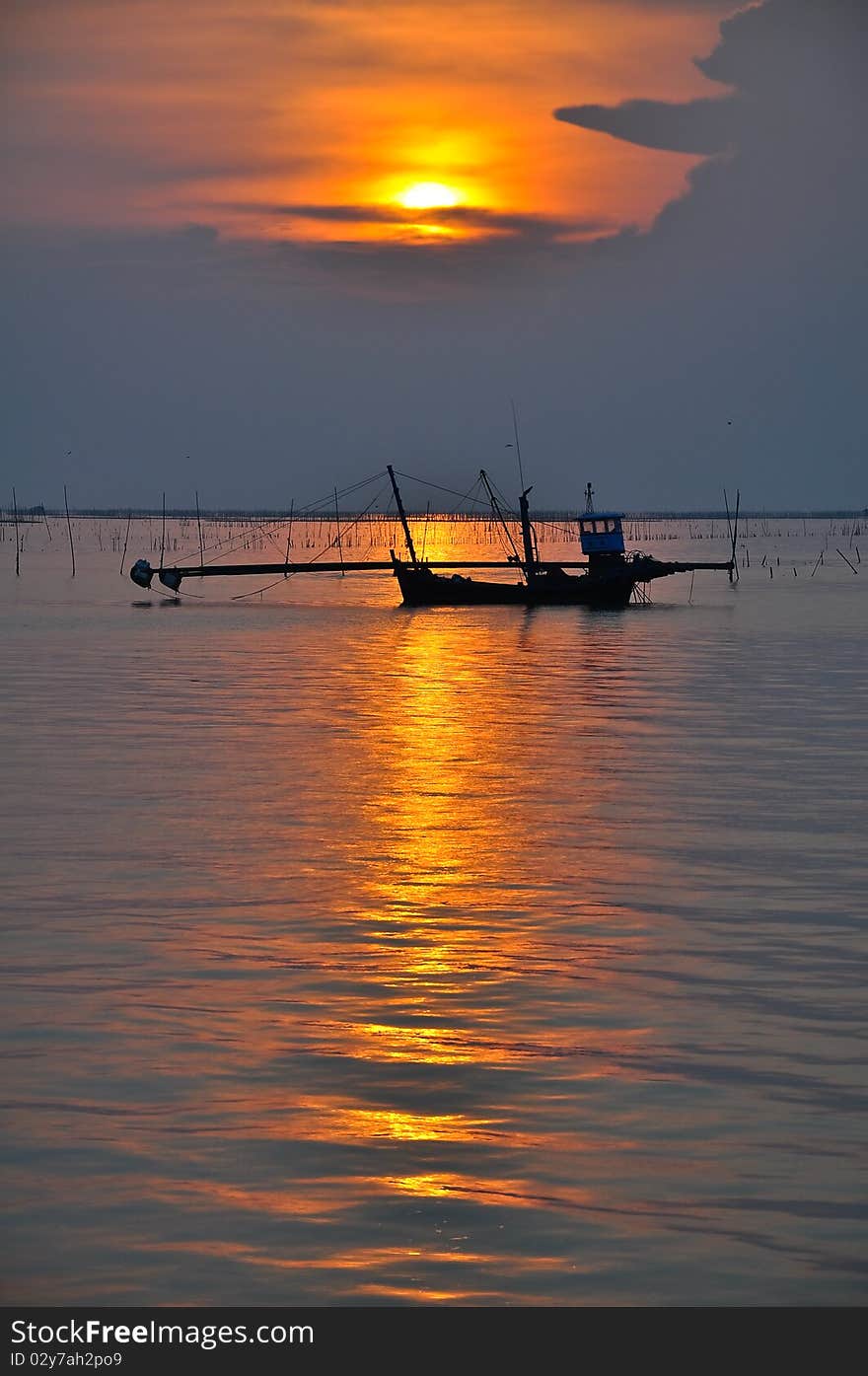 Silhouette of fishing boat in sunset over the sea