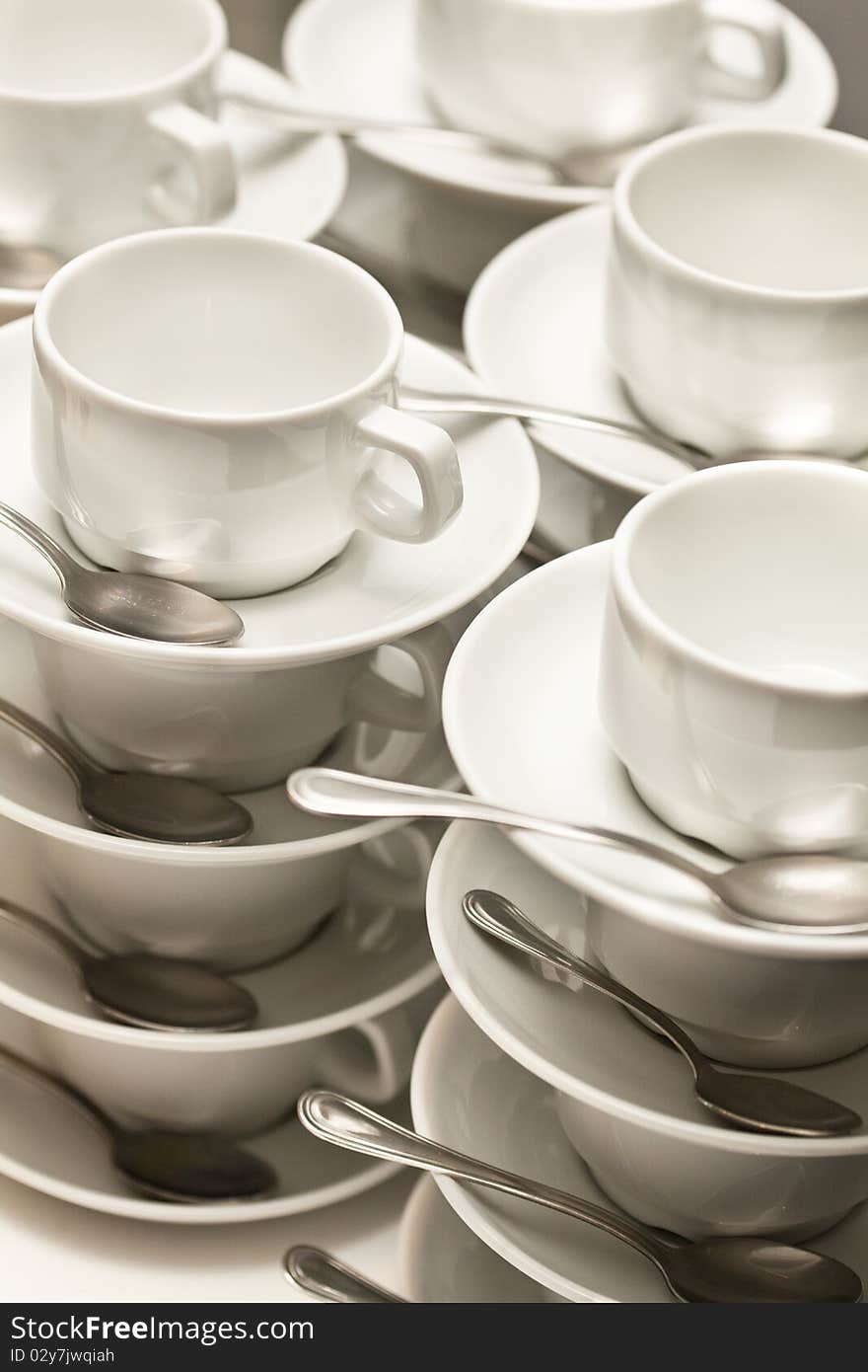 Stacked empty teacups with teaspoons at a function over white background