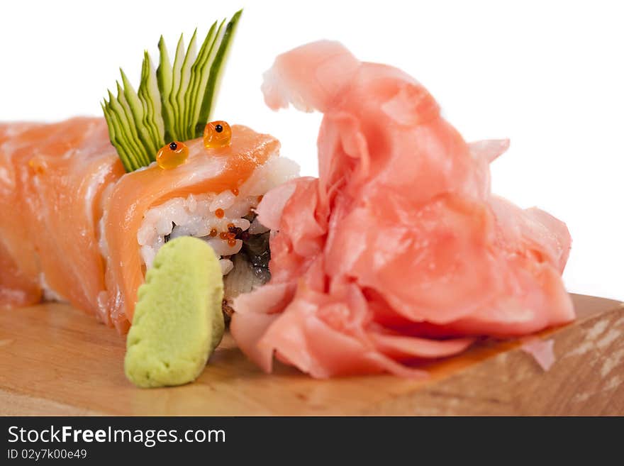 Red sushi Dragon devouring ginger on a wooden board against white background. Red sushi Dragon devouring ginger on a wooden board against white background