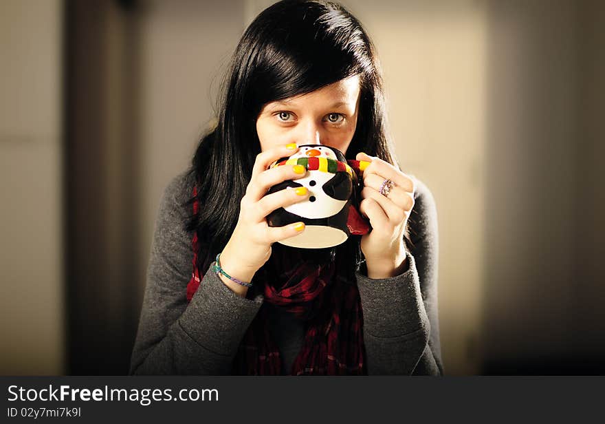 Girl staying warm drinking from a penguin cup. Girl staying warm drinking from a penguin cup