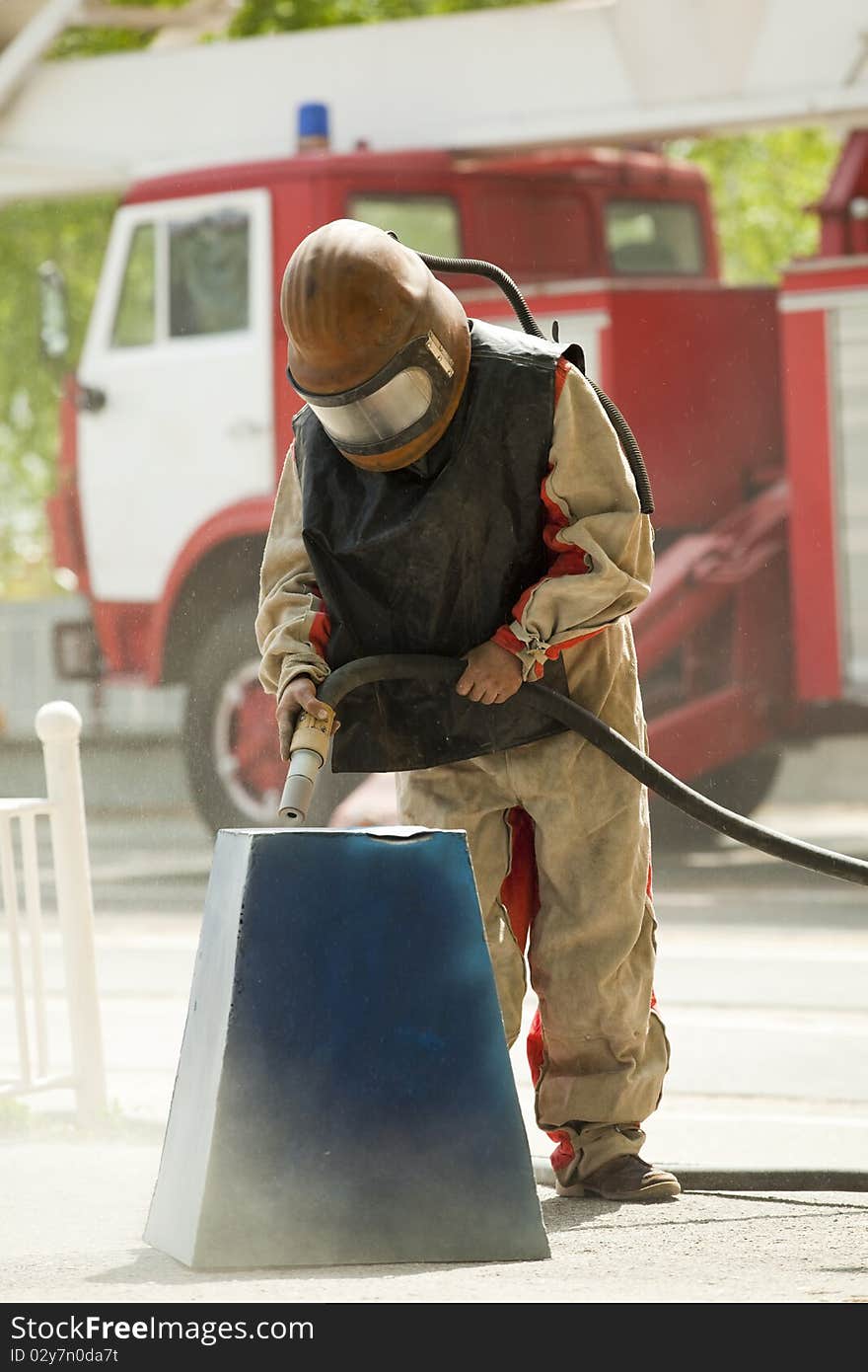 Worker in a protective suit spraying sand