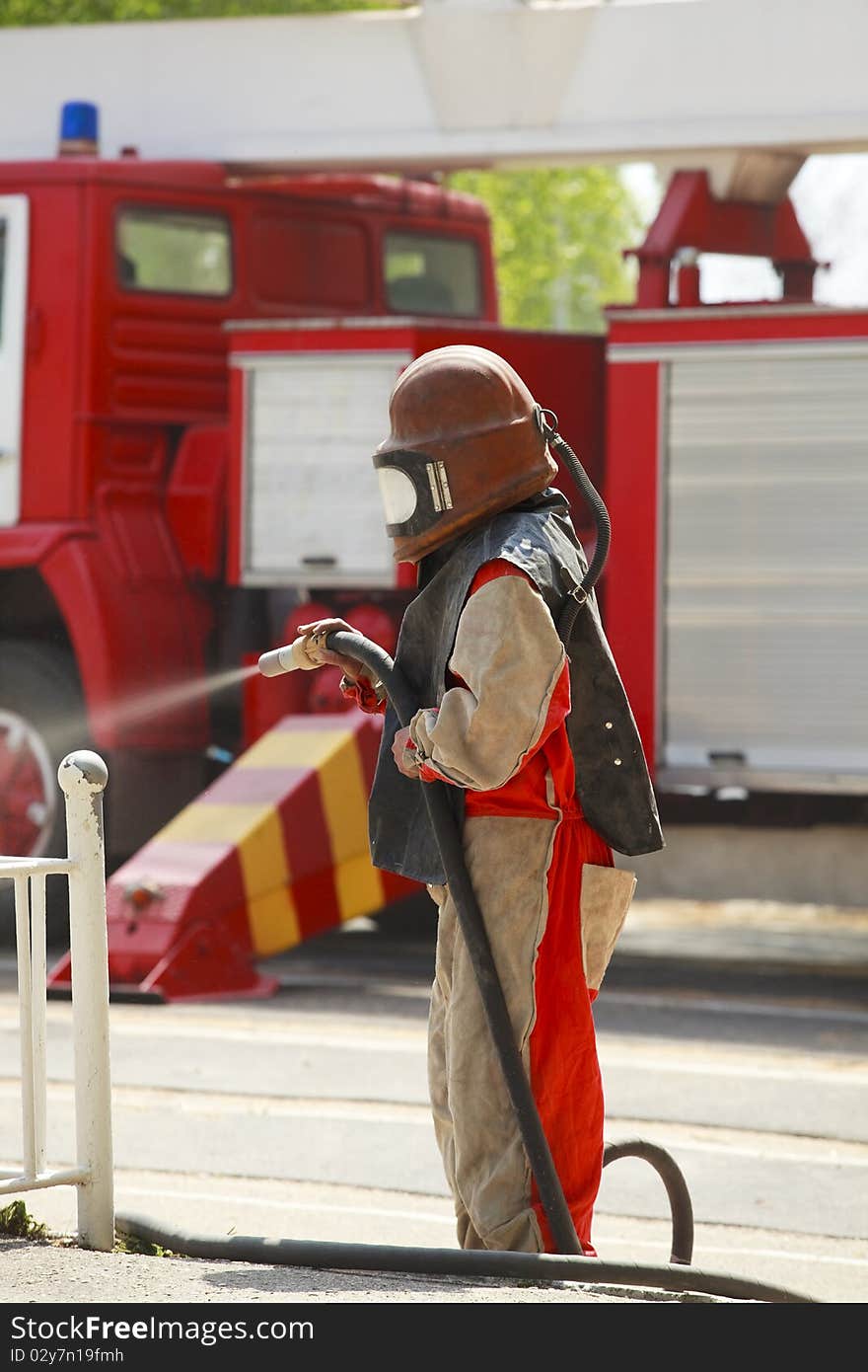 Worker in a protective suit spraying sand