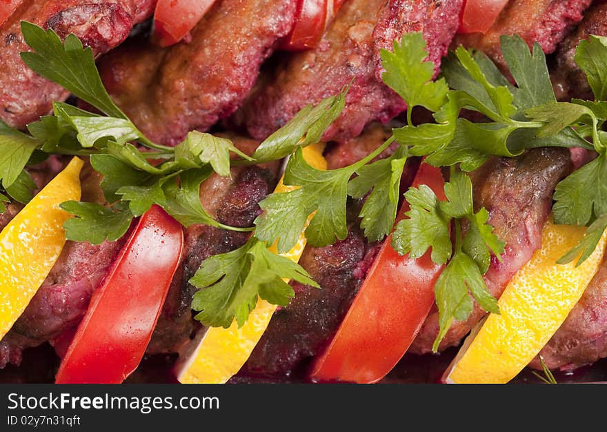 Macro shot of baked fish, tomato and lemon slices decorated with cucumber and parsley