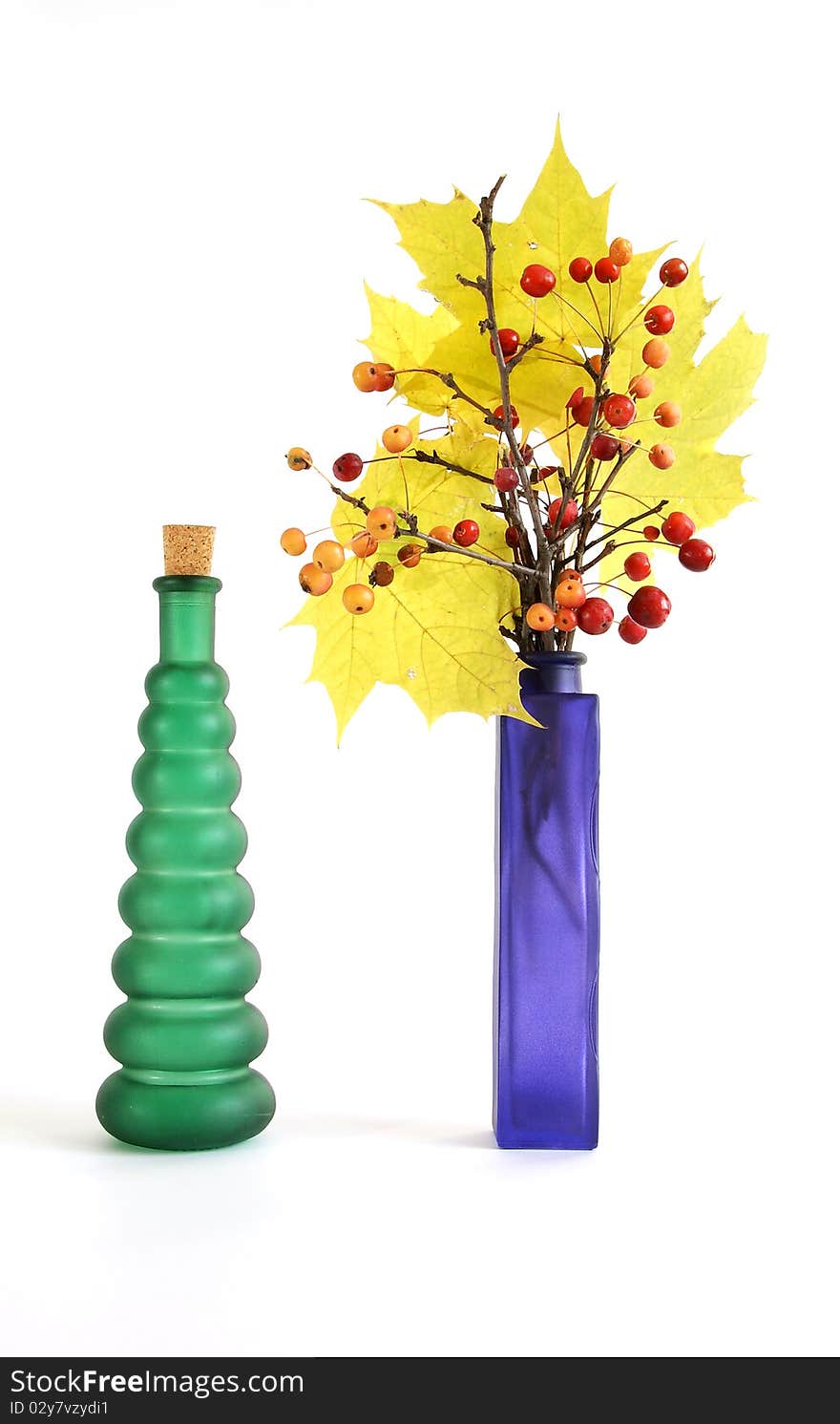 Autumn bouquet of branches with small apples and maple leaves to color a glass vase on a white background