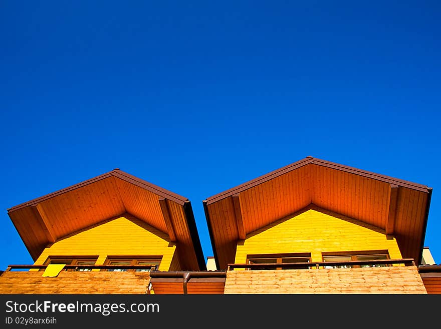 Part of yellow, wooden house under the clear, blue sky. Part of yellow, wooden house under the clear, blue sky.