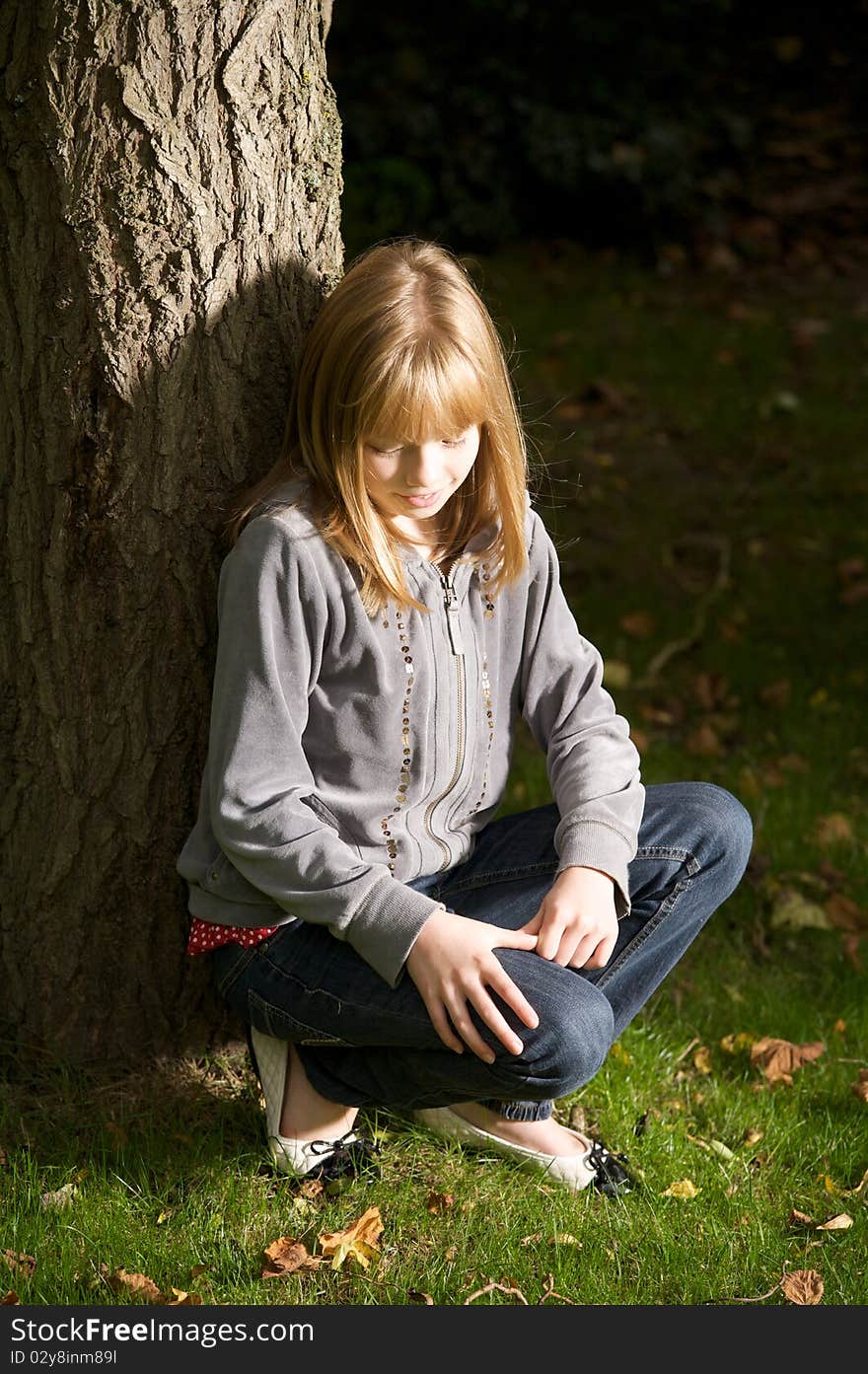 Young girl smiling and leaning on a tree. Young girl smiling and leaning on a tree