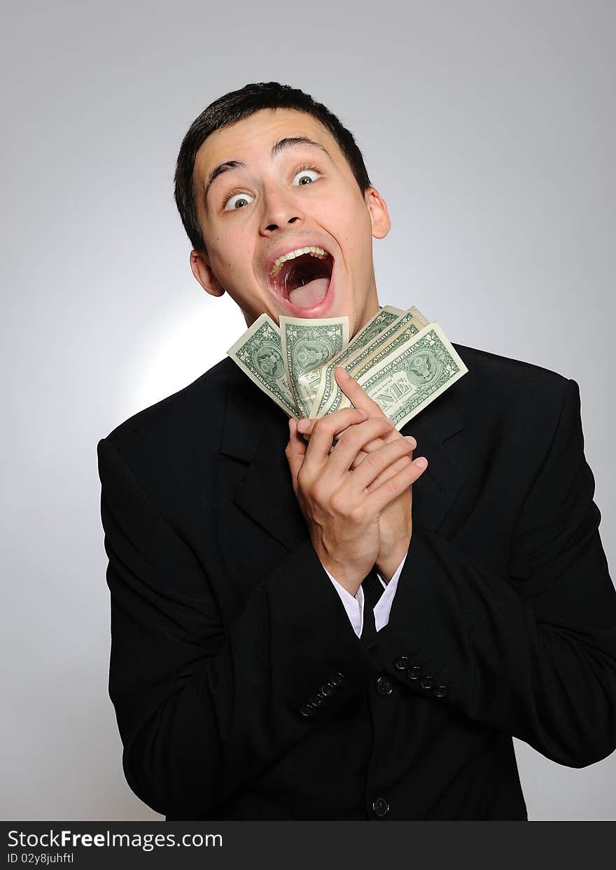 Expressions - Young handsome business man in black suit and tie counting money. gray background. Expressions - Young handsome business man in black suit and tie counting money. gray background