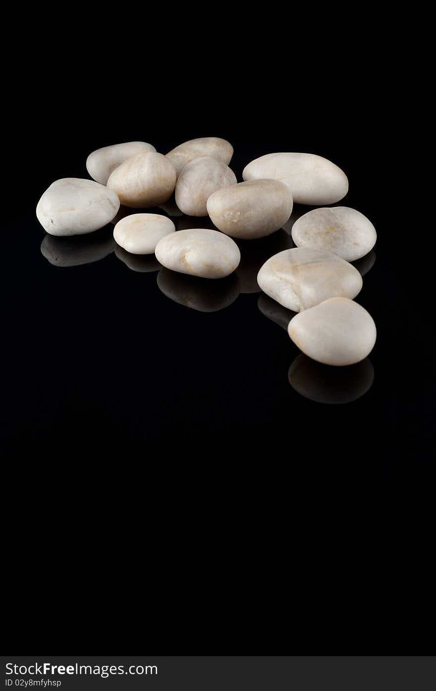 White stones on black background, mirror surface