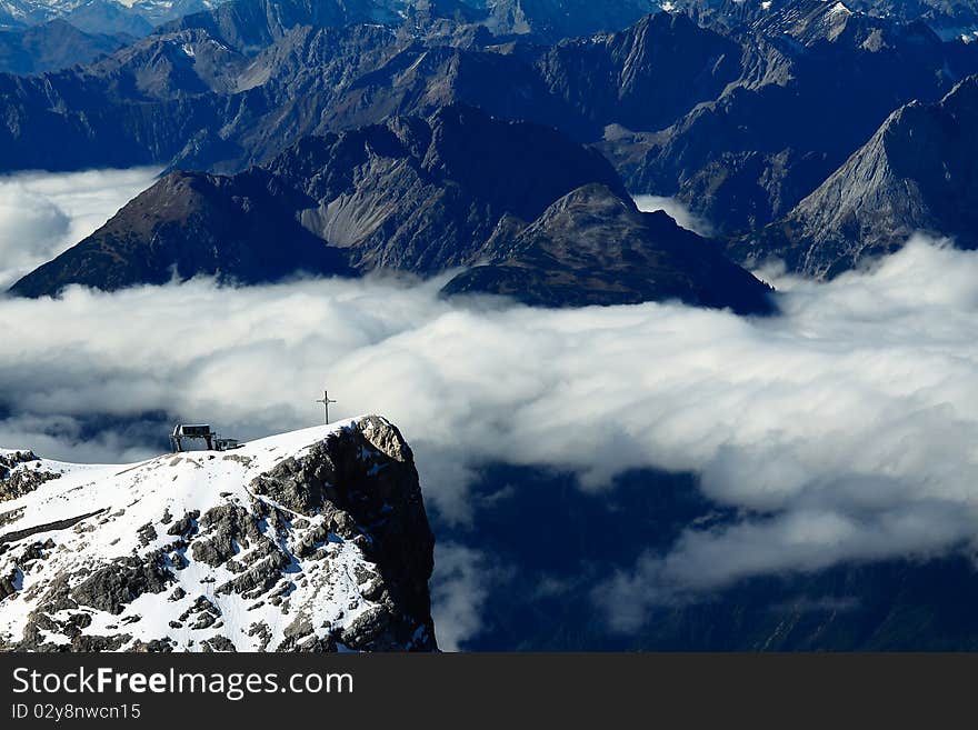 Cross of zugspitze surrounded by a lot of mountains