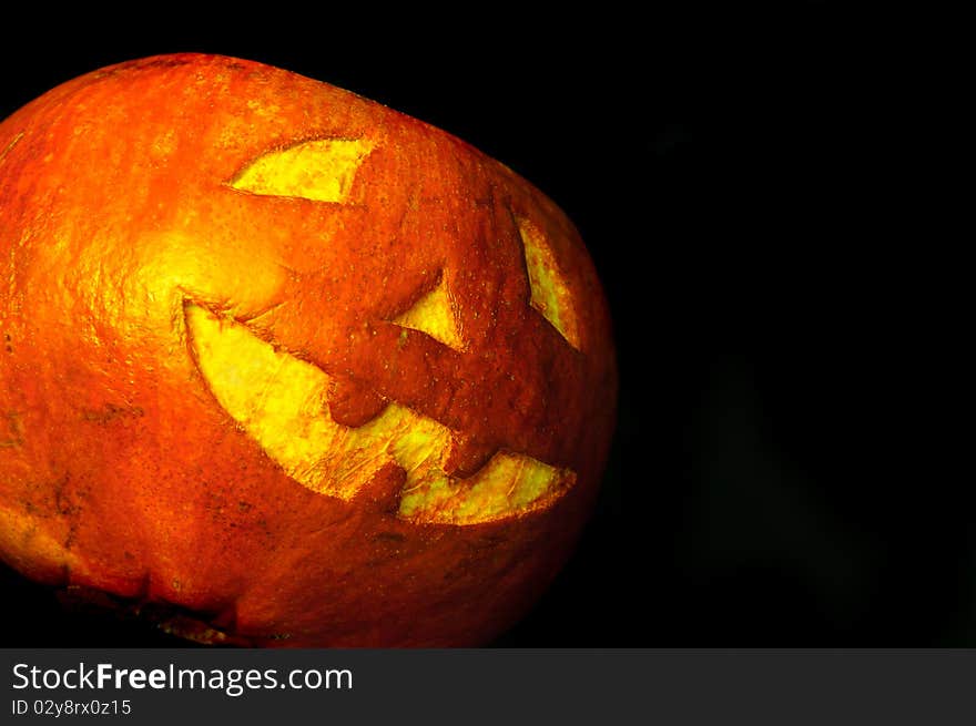 Halloween face cut out on fruit. Isolated on black. Halloween face cut out on fruit. Isolated on black