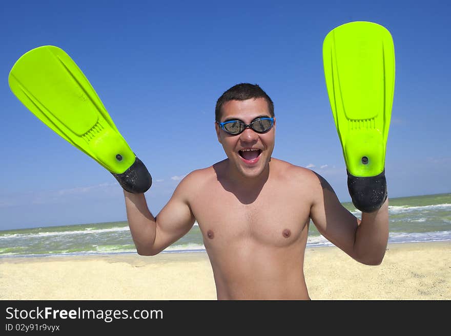 Portrait of smiling boy in swimming mask and fins on his hands against the sea and sky