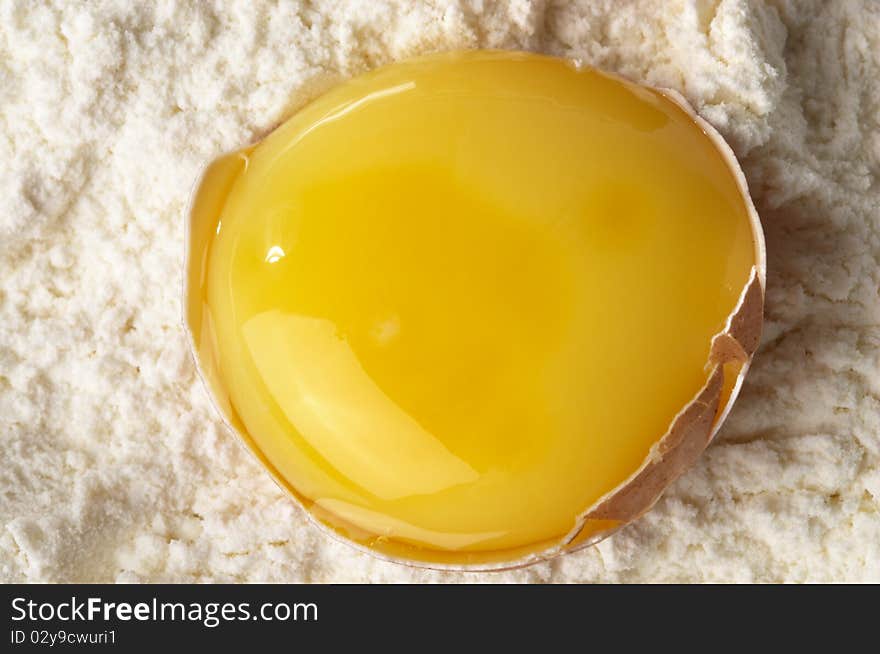 Broken eggshell and yolk in the flour macro shot. Broken eggshell and yolk in the flour macro shot