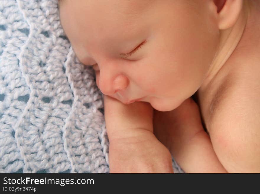 Newborn baby boy sleeping on a knitted blanket