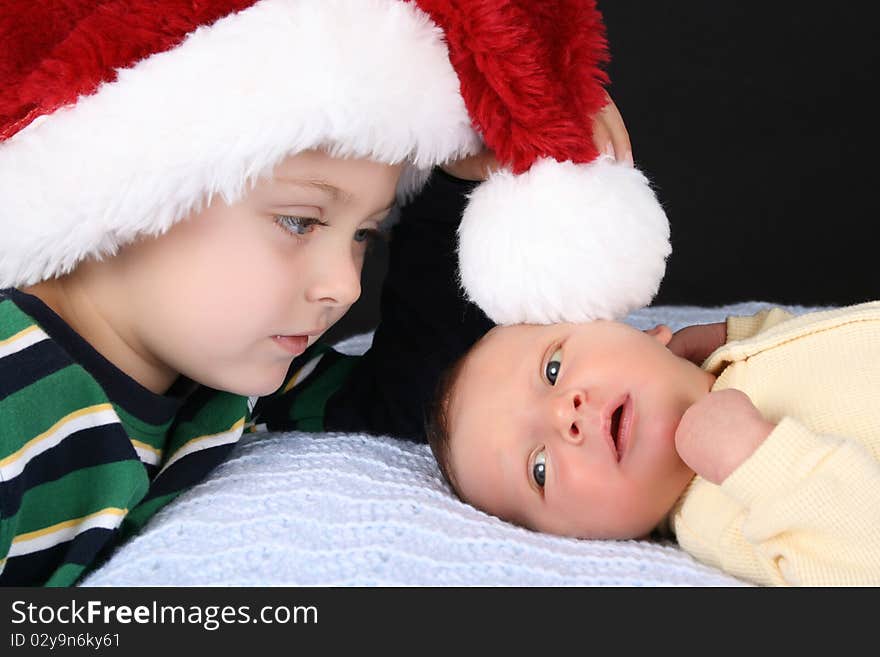 Boy wearing a christmas hat with his newborn brother. Boy wearing a christmas hat with his newborn brother