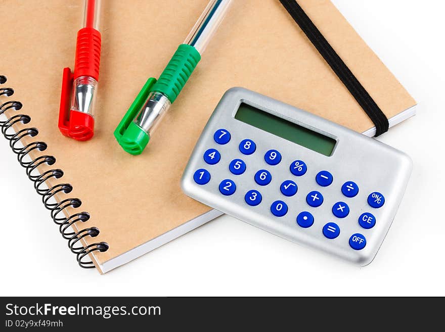 Red and Green pen on a brown notepad with a simple calculator. Red and Green pen on a brown notepad with a simple calculator