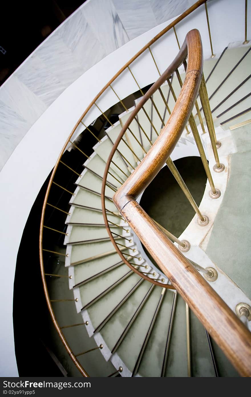 Bended brown wooden handhold of spiral stone stairs. Bended brown wooden handhold of spiral stone stairs