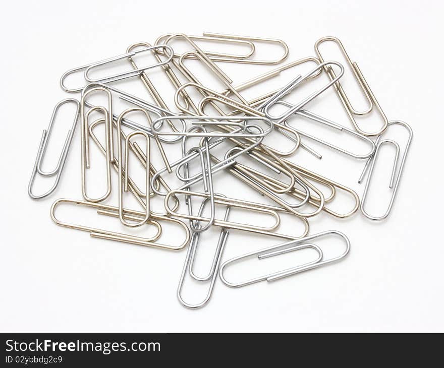 Writing metal paper clips lie in bulk on a white background of a paper