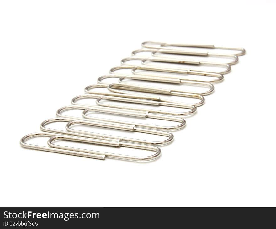 Writing metal paper clips lie in bulk on a white background of a paper