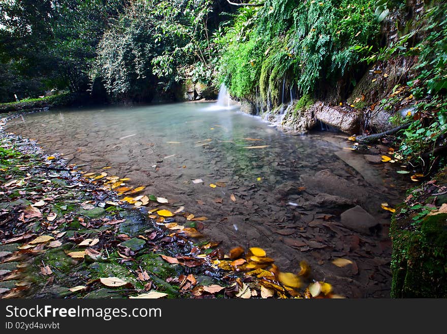 A small lake with a waterfall in autumn