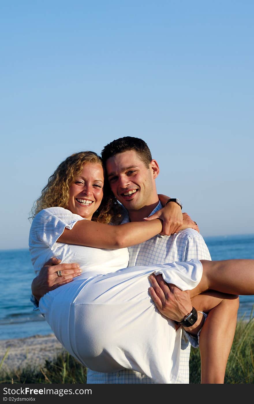 A happy woman and man in love at beach. The the young man is lifting his girlfrind. A happy woman and man in love at beach. The the young man is lifting his girlfrind.