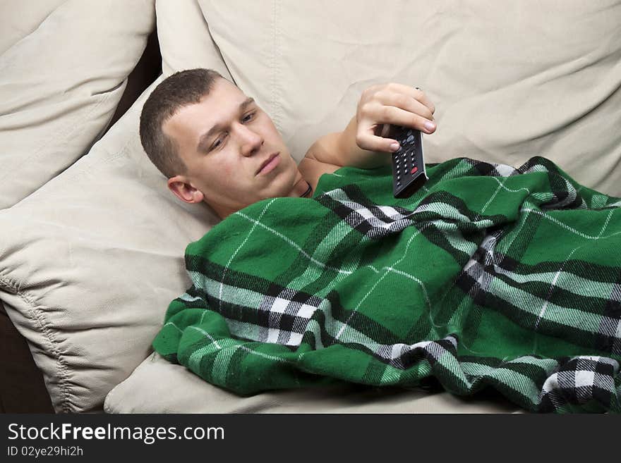 Casual man, lying on the couch, watching television with the command at hand. Casual man, lying on the couch, watching television with the command at hand