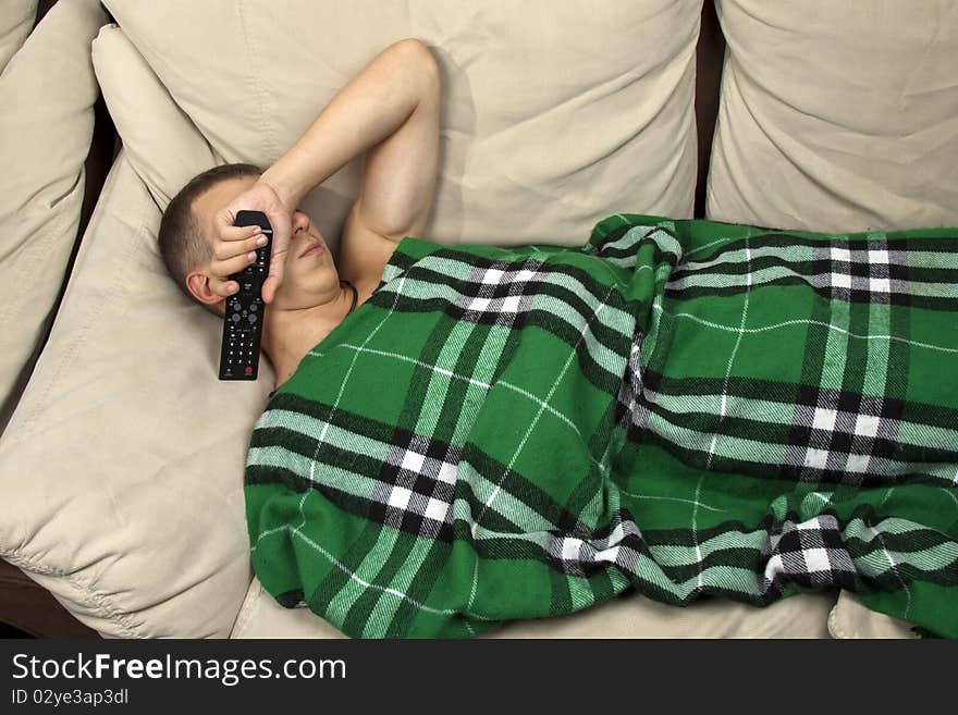 A young man sleeping on the couch with remote control. A young man sleeping on the couch with remote control